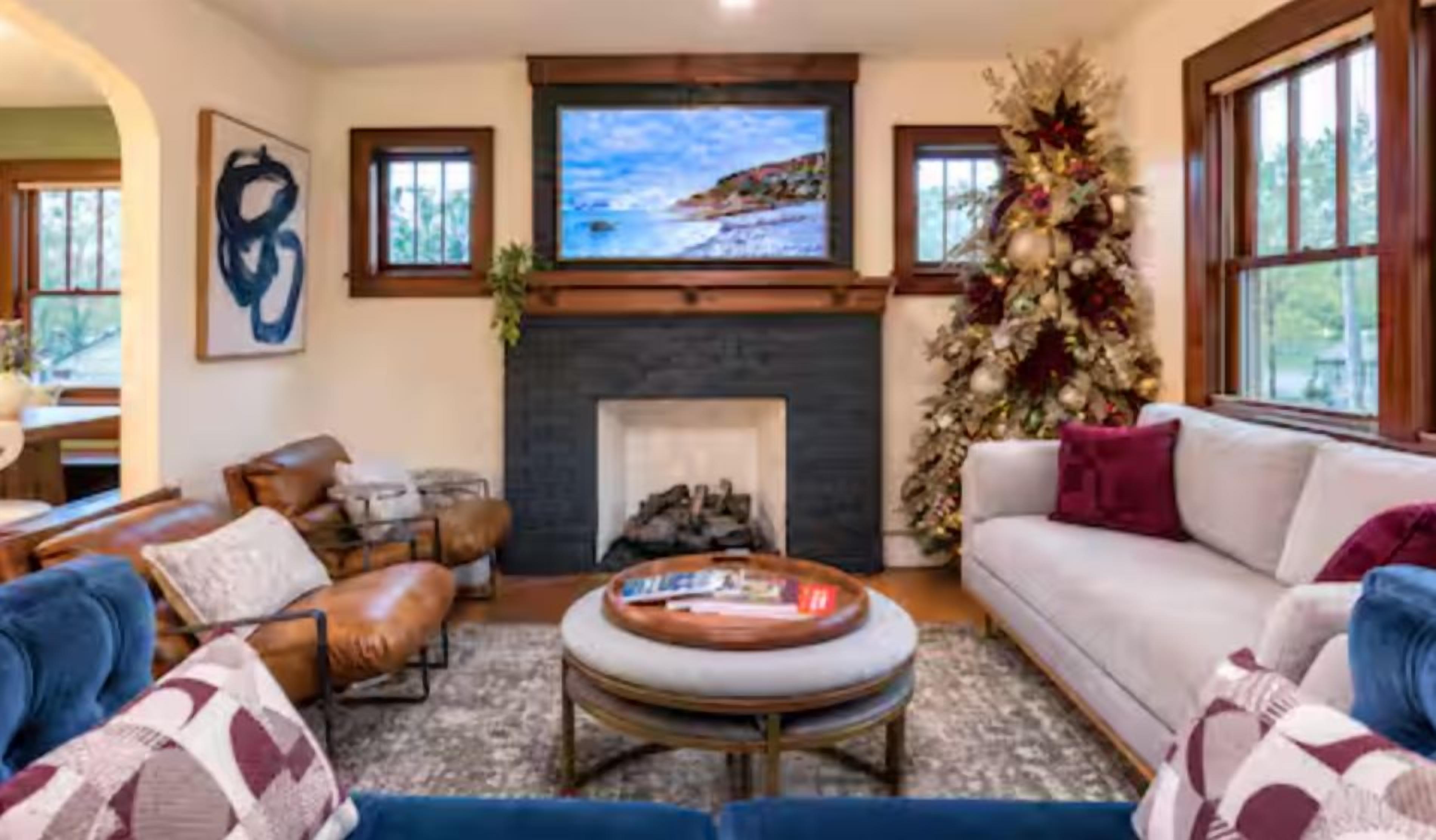 Una sala de estar con chimenea, un televisor montado sobre ella y un árbol de Navidad.