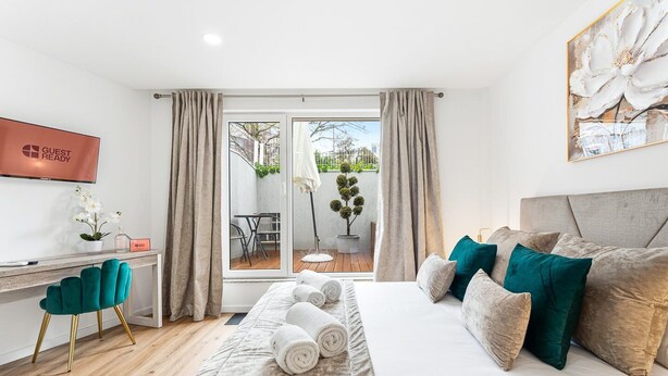 Ein Hotelzimmer mit Bett, Schreibtisch, Stuhl, Fernseher und Blick ins Freie.