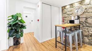 Ein Hotelzimmer mit Holzboden, einem Tisch mit eingebauter Mikrowelle, einer Wanduhr und einem Blumentopf.