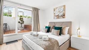 Ein modernes Schlafzimmer mit einem großen Bett, Blick auf die Stadt und einem Balkon mit Pflanzen.