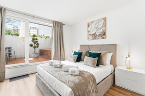 Ein modernes Schlafzimmer mit einem großen Bett, Blick auf die Stadt und einem Balkon mit Pflanzen.