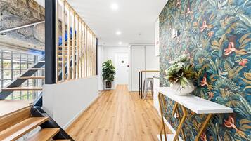 A modern interior with a wooden staircase, a plant, and a vibrant floral wall.