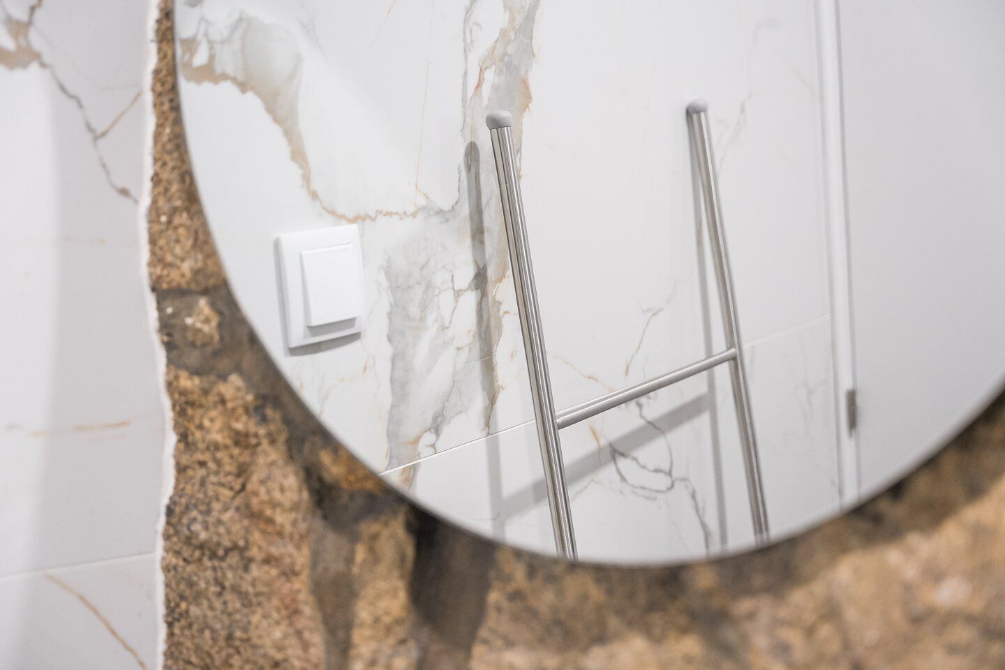 Une salle de bain avec un mur en marbre, un tableau électrique blanc et un porte-serviettes en métal.