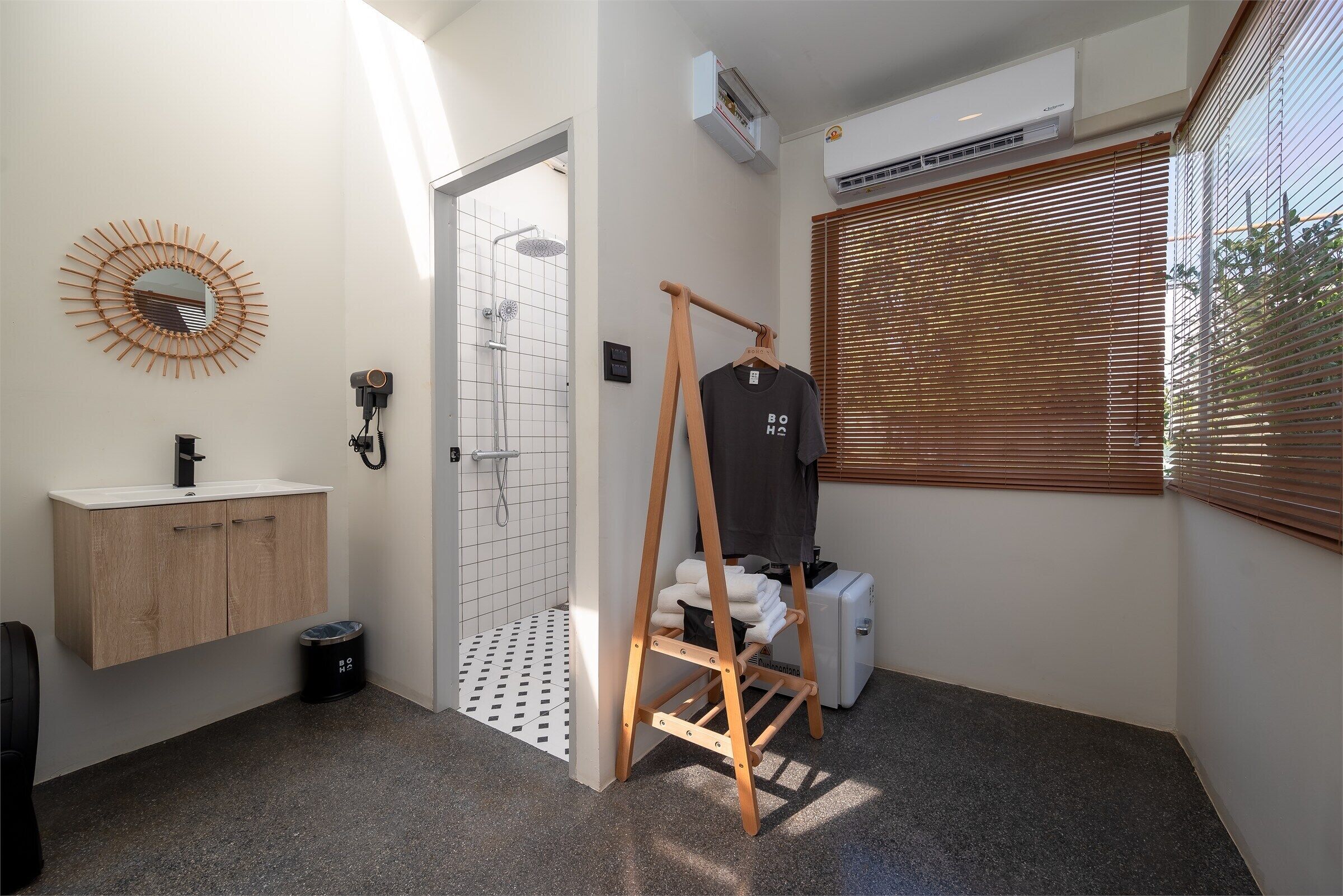 Un baño con tocador de madera, perchero, ducha y ventana con persianas.