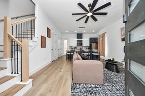 Ein modernes Interieur mit Treppe, Deckenventilator, Küchenzeile und Sitzgelegenheit.