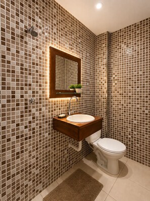 A bathroom with a tiled wall, a sink, a mirror, a toilet, and a showerhead. - Studio apartment in the city center with Wi-Fi. (Manaus)