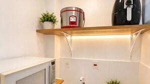 A compact kitchen with a microwave, a rice cooker, a coffee maker, a sink, and a small refrigerator. - Studio apartment in the city center with Wi-Fi. (Manaus)