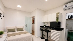 A compact room with a bed, a kitchenette, and a seating area. - Studio apartment in the city center with Wi-Fi. (Manaus)