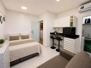 A compact room with a bed, a kitchenette, and a seating area. - Studio apartment in the city center with Wi-Fi. (Manaus)