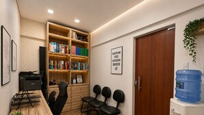 A conference room with a wooden table, chairs, a bookshelf, a water dispenser, and a motivational poster. - Studio apartment in the city center with Wi-Fi. (Manaus)
