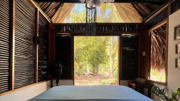 A room with a bed, a ceiling fan, and a view of the outdoors. - Hospedaje Villa creta (Cartagena)