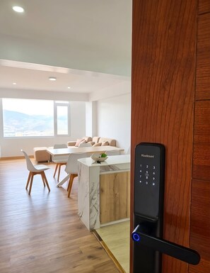 A modern living room with a wooden floor, a marble accent wall, a sofa, and a dining area with chairs and a table. - Cusco Nest Apt 2 - Spacious 3-Bedroom Apartment in Cusco (Cusco)