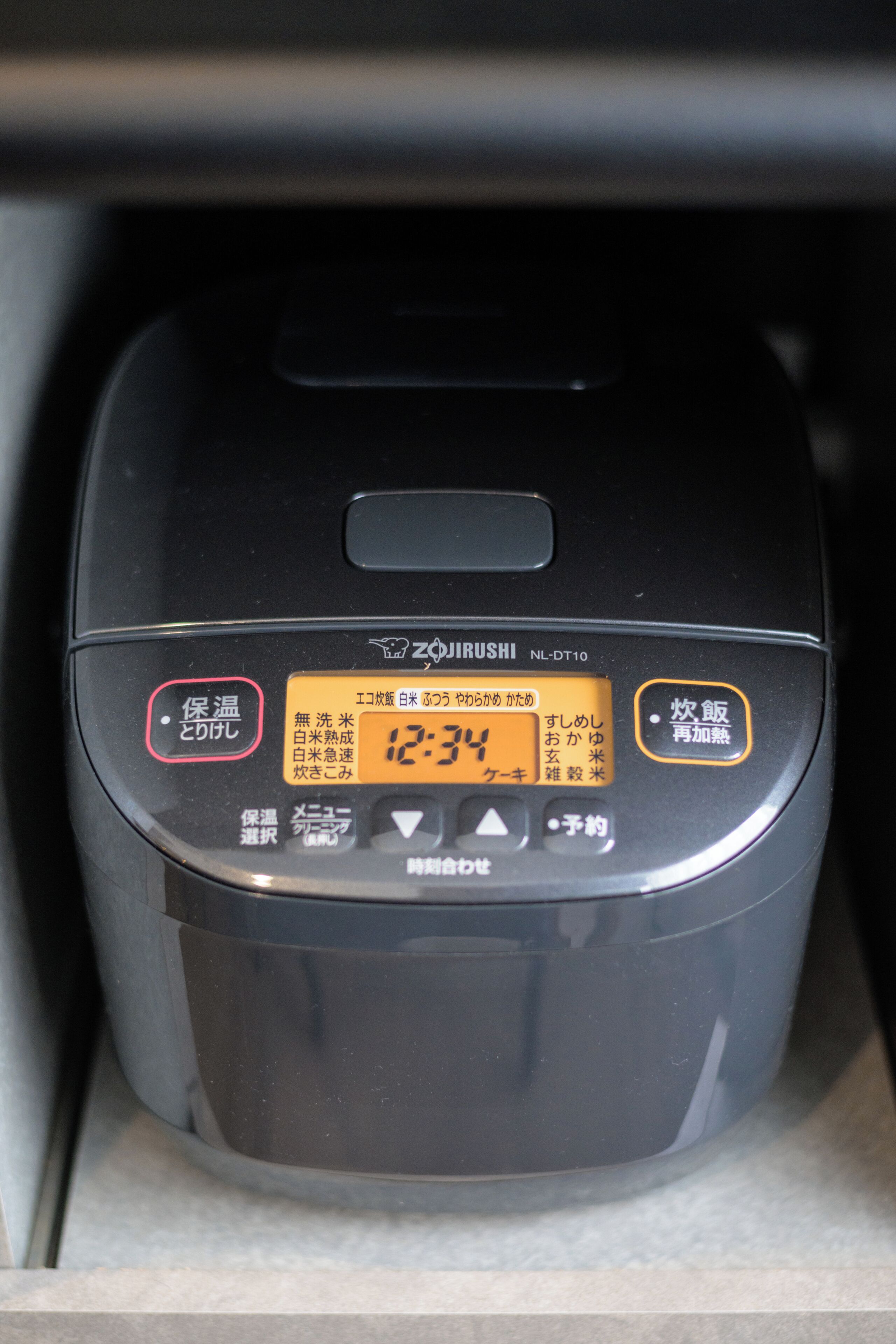 A black rice cooker with Japanese text and a digital display.