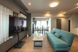 A modern living room with a sofa, a dining table, and a kitchen area.
