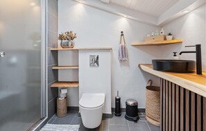 Un baño moderno con inodoro, lavamanos y estantes.