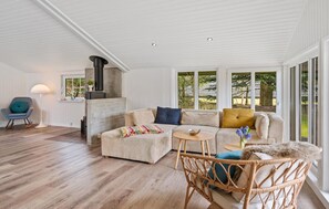 A room with a sectional sofa, a wicker chair, a small round table, and a fireplace. - Lovely home in Oksbøl with WiFi (Oksbøl)