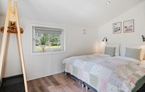 Un dormitorio con cama, ventana, escalera de madera y dos luces fijadas a la pared.