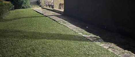 A building with a stone facade, a paved pathway, and a well-maintained lawn.