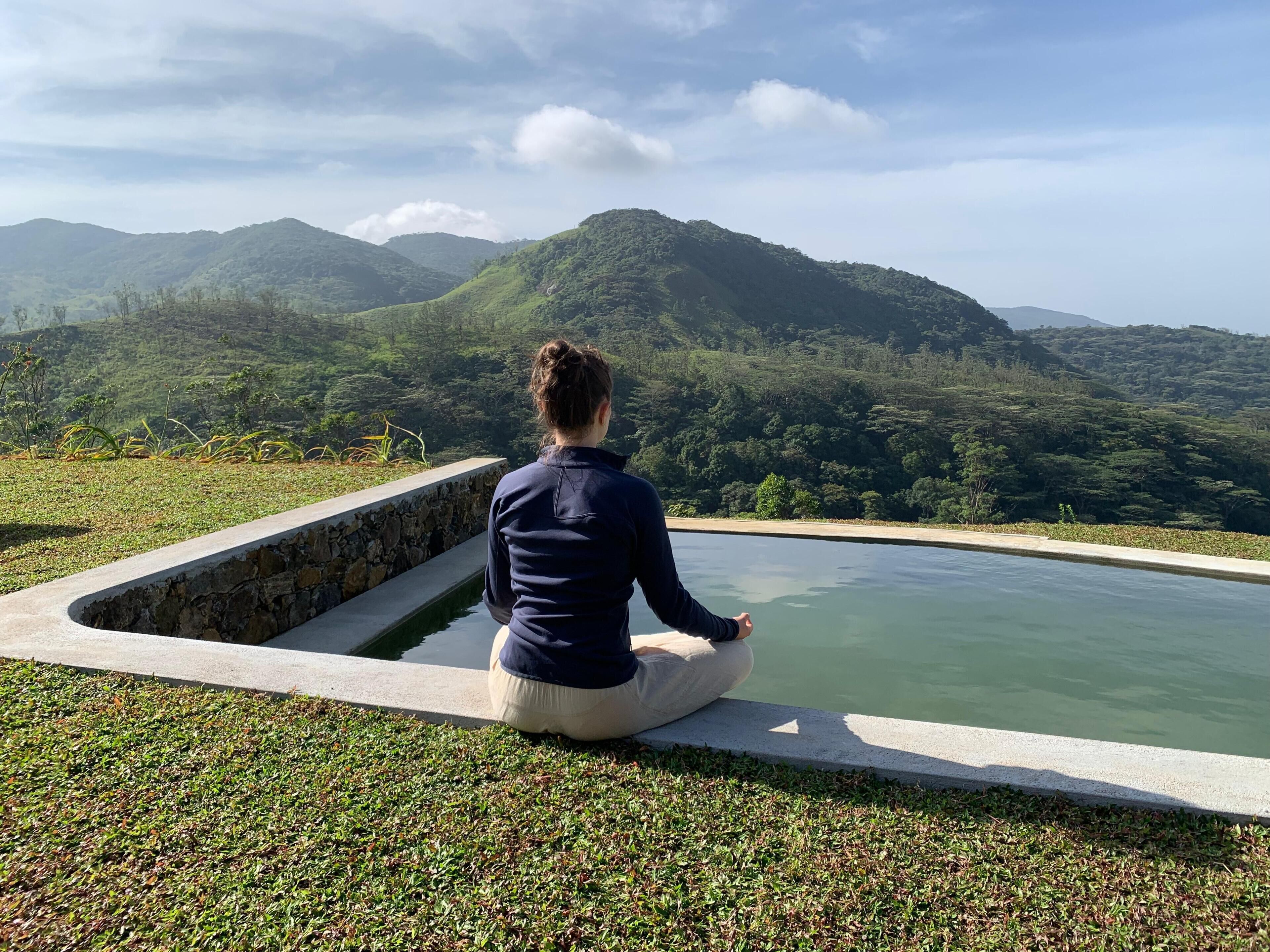 A person sitting by a pool with a view of mountains.