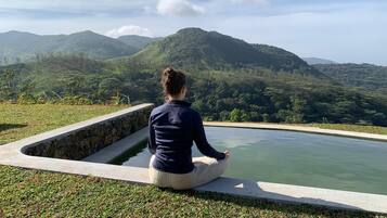 A person sitting by a pool with a view of mountains.