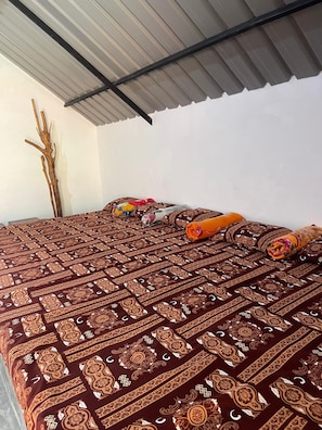 Una cama con colcha estampada, una rama decorativa y toallas enrolladas.