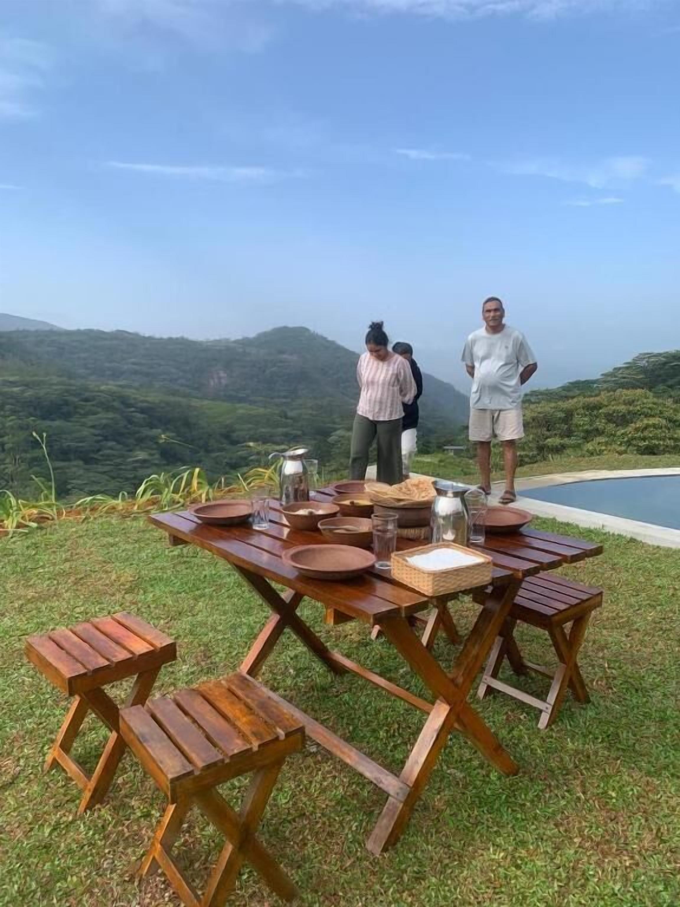 A wooden dining table set outdoors with a scenic mountain view in the background.