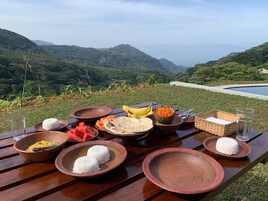 Una mesa de picnic con diversos alimentos y una vista panorámica de colinas.