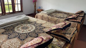 Ein Zimmer mit zwei Betten, einem Fenster mit Blick, einem kleinen Tisch mit Wasserflaschen und einem Gegenstand an der Wand.