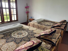 Habitación con dos camas, ventana con vistas, una mesita con botellas de agua y un objeto fijado a la pared.