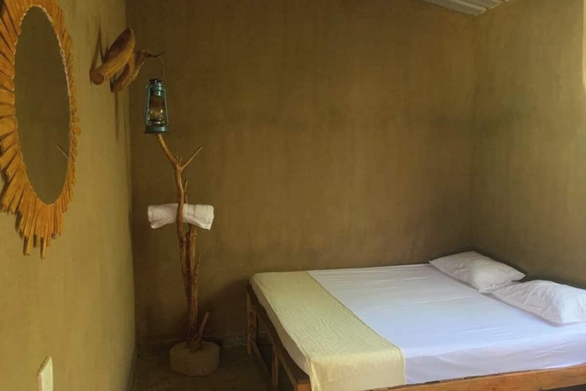 Una cama individual con ropa blanca, cabecera de madera y una mesita de noche pequeña.