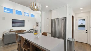 A modern kitchen with a large island, stainless steel appliances, and a dining area with a TV. - Private Mid-Century Oasis 3-bedroom home  in  Los Angeles with Pool/Spa & BBQ (Los Angeles)