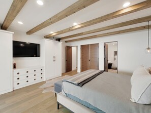 Un dormitorio con cama, armario, televisor y espejo.