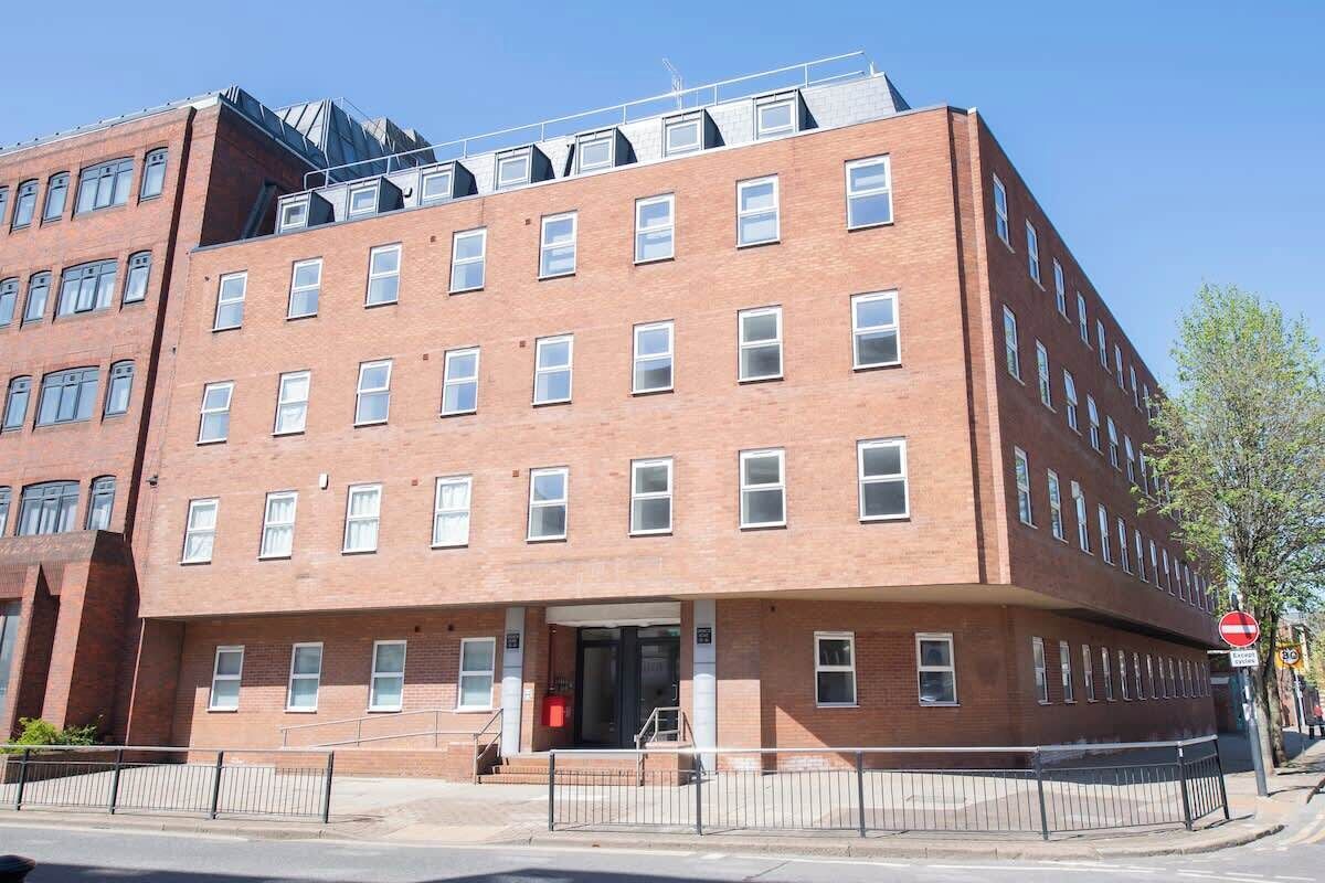 A multi-story brick building with a flat roof, large windows, and a visible entrance.