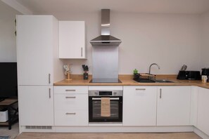 Eine moderne Küche mit weißen Schränken, einer Edelstahl-Dunstabzugshaube, einem Einbauofen und einer Holz Arbeitsplatte.