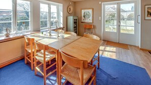 Un comedor con una mesa y sillas de madera, ventanas amplias y vistas al exterior.