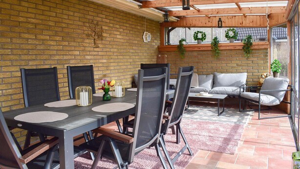 A covered patio with a brick wall, a wooden ceiling, and a seating area with a sofa and chairs. - 3 bedroom cozy home in Degeberga (Degeberga)