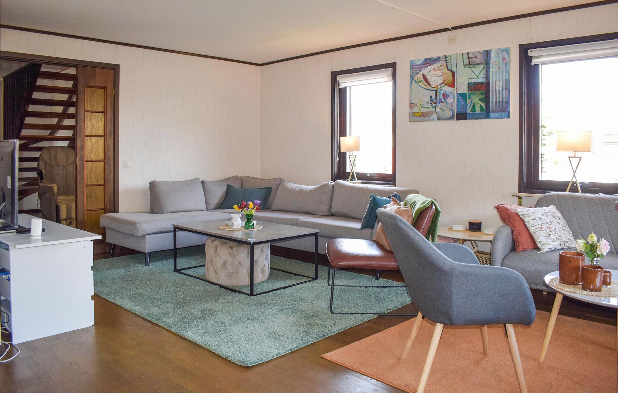 A living room with a sofa, armchairs, a coffee table, a TV, and artwork on the walls.
