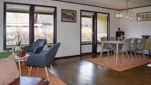 A modern living room with a sofa, chairs, a dining table, and a kitchen area with a guitar. - 3 bedroom cozy home in Degeberga (Degeberga)