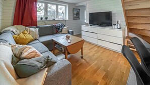 Olohuone, jossa on sohva, sohvapöytä, televisio ja pieni kaappi.