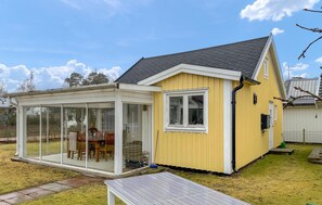 Ett gult hus med en inglasad veranda och ett fönster.