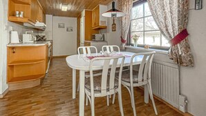 A compact kitchen with a dining table, chairs, and a window with curtains.