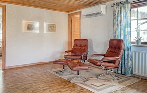 A room with two leather recliners, a wooden floor, a patterned rug, and a window with curtains.