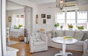 A well-lit room with a white sofa, a round table, and a window with plants. - Pet friendly home in Jämjö with house sea view (Jämjö)