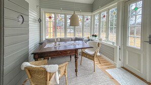 Un coin repas avec une table en bois, des chaises en osier et un banc.