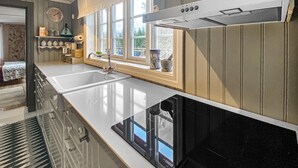 Une cuisine équipée d’un évier à deux bacs, d’une cuisinière et d’une fenêtre donnant sur les arbres.