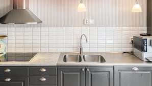 Una cocina con un lavamanos de acero inoxidable, un microondas y una campana extractora.