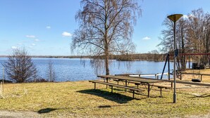 Un área de picnic junto al lago con bancos, un columpio y una farola.