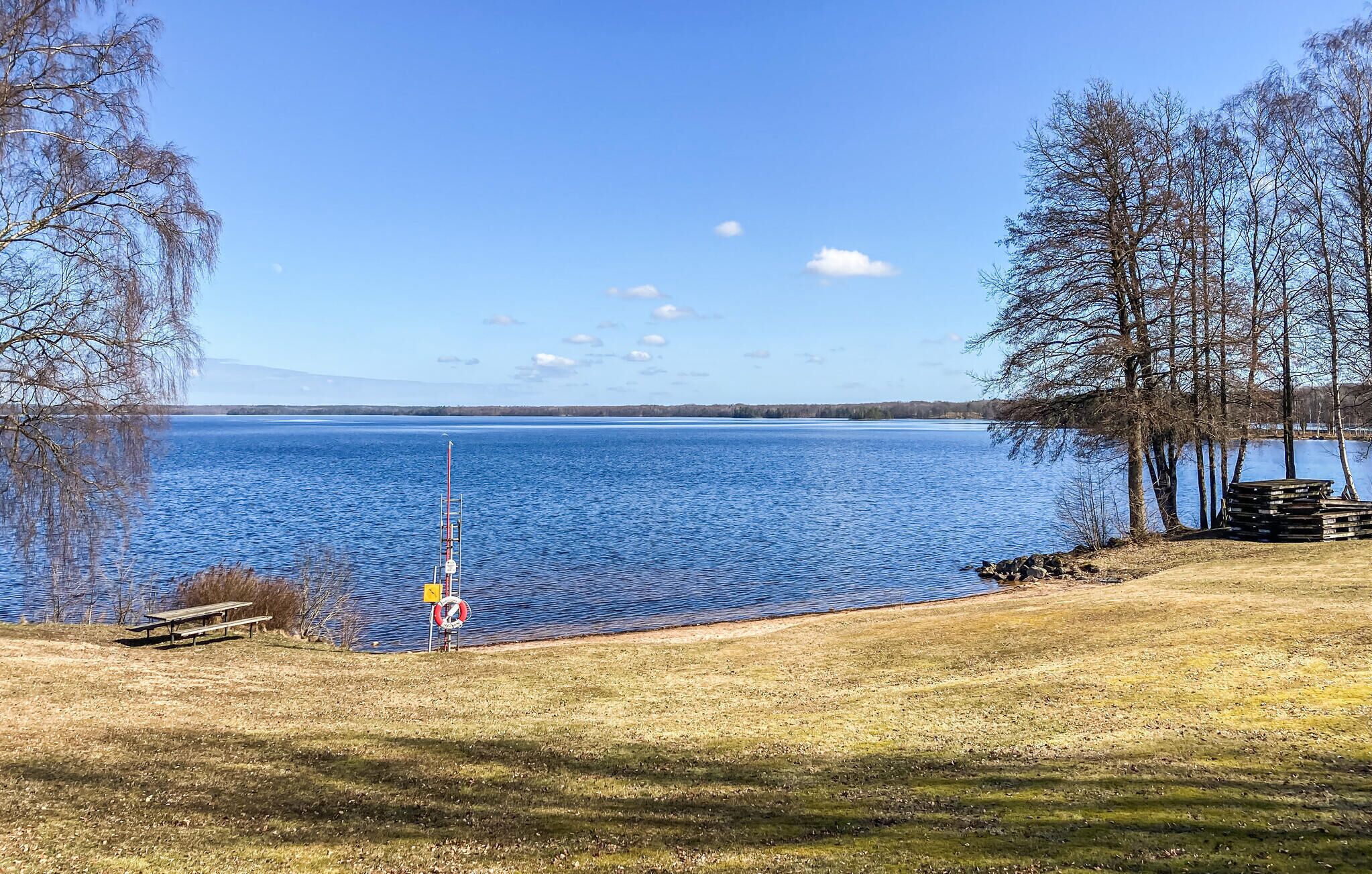 Une vue sur le lac, avec une table de pique-nique, une bouée de sauvetage et un mât.