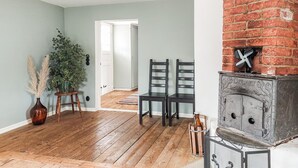 Een kamer met een open haard, twee stoelen, een potplant en een houten vloer.