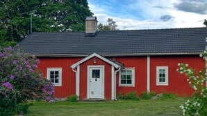 Een rode woning met een witte deur, twee ramen en een schoorsteen.